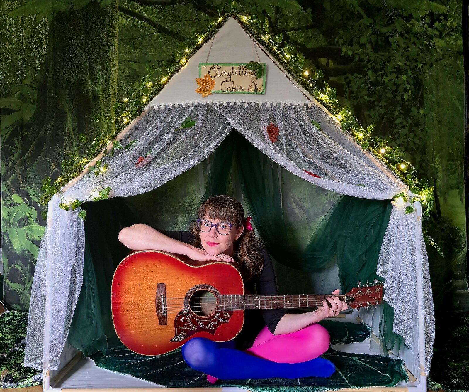 Aga playing guitar outside the storytelling cabin